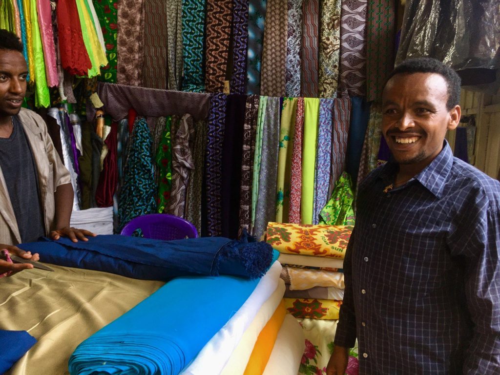 Bires Gashu smiles with a fabric seller as he purchases material for his clothing business.