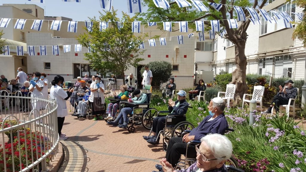 A number of elderly people attend a JDC and Weinberg Foundation organized "party" in a nursing home garden.