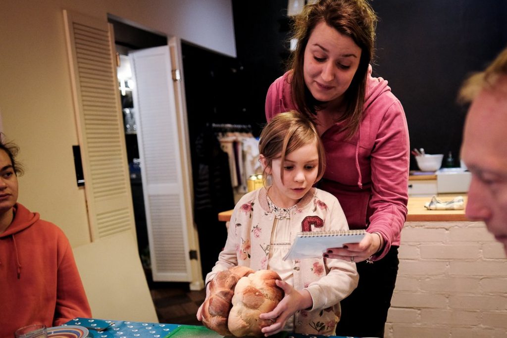 Maria with a young girl who holds challah at a challah making class.