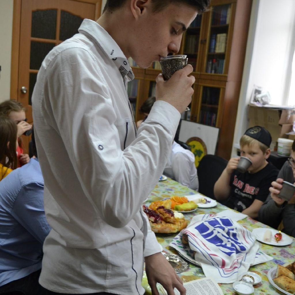 Anton drinks wine at a Shabbat event, before coronavirus.