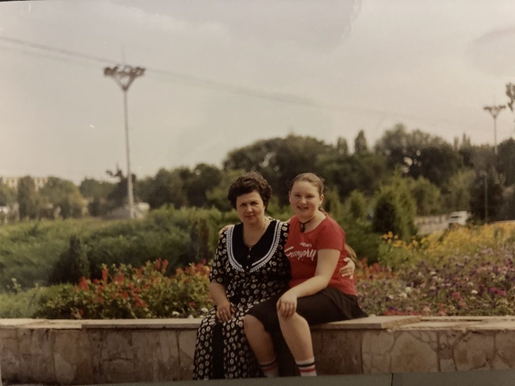 Marina and her mother, visiting Moldova in 1995. They sit on a bench with the countryside in the background.