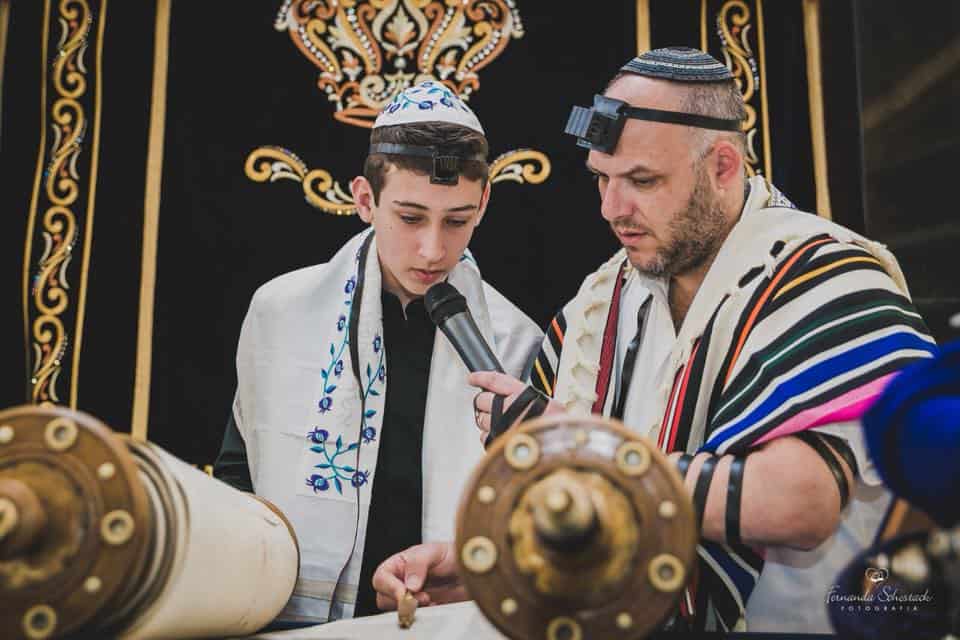 Rabbi Oliszewski helps a bar mitzvah read from the Torah.