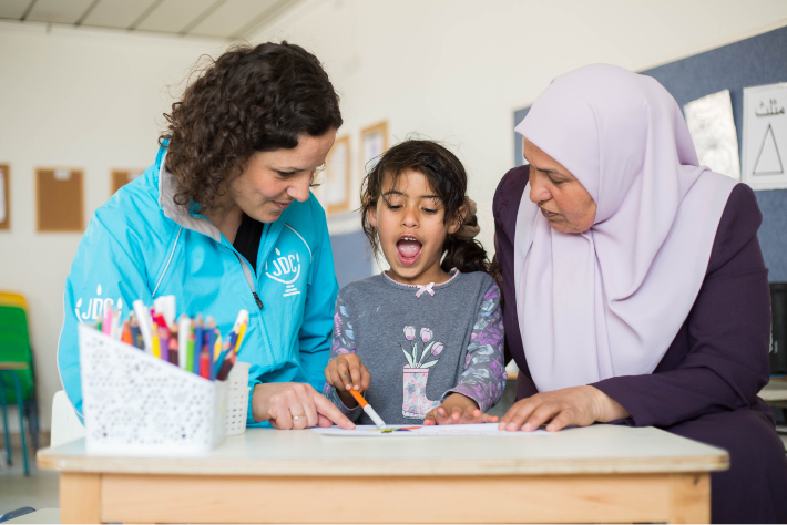 JDC volunteer teaches young Israeli Arab girl to read.