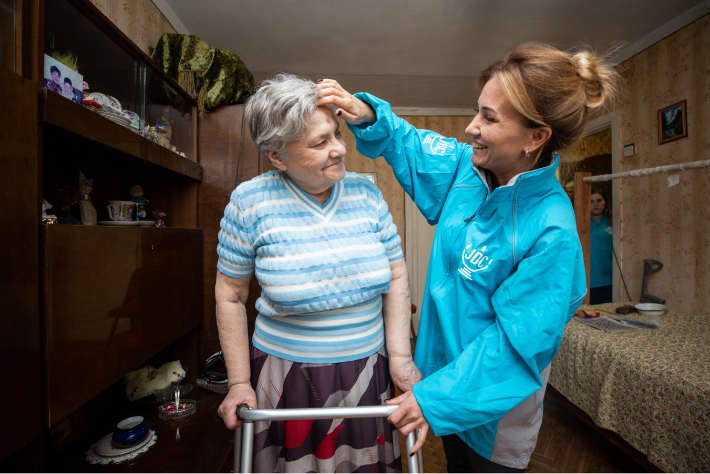 JDC volunteer in the former Soviet Union brushing the hair of an elderly female client with a walker.