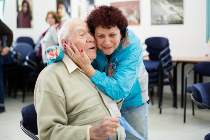 JDC volunteer embraces elderly male client in Israel.