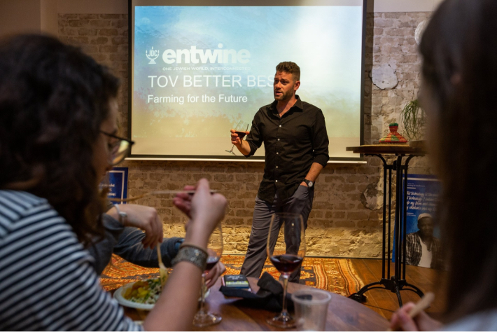 JDC Entwine speaker holding a glass of red wine while presenting on Tikkun Olam Ventures (TOV).