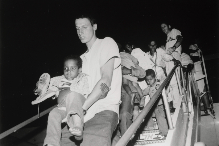 A JDC volunteer carrying an Ethiopian-Jewish boy down from a flight during Operation Solomon.