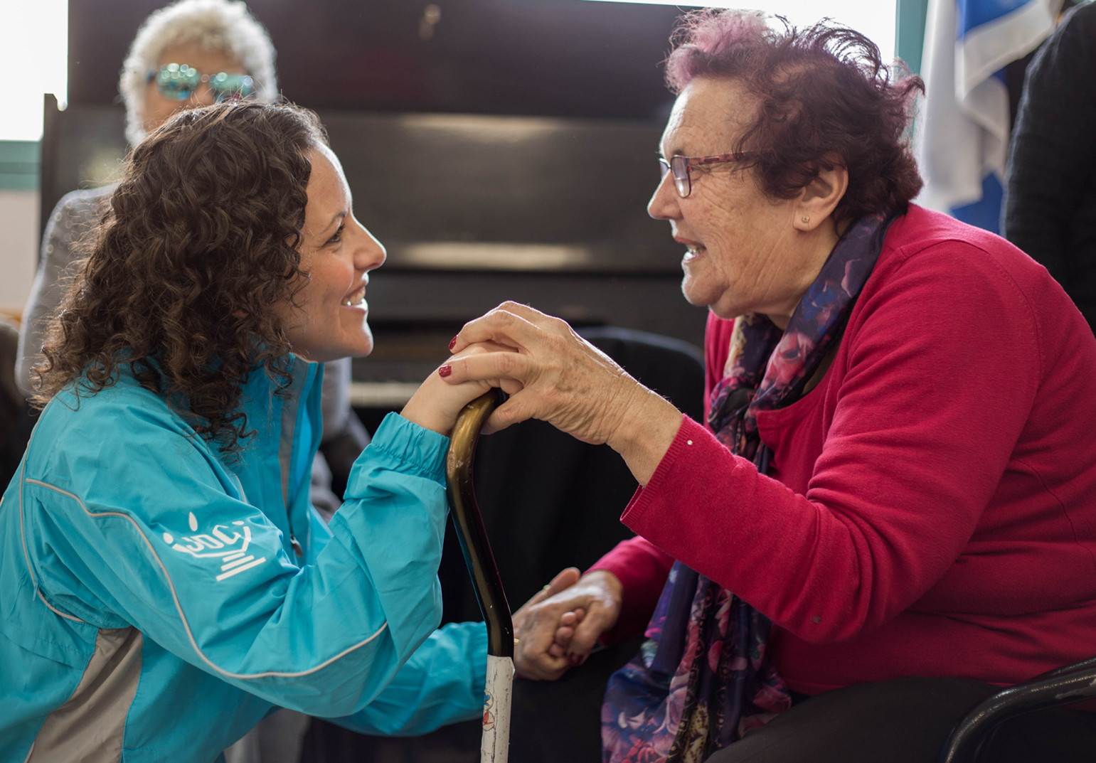 A JDC volunteer speaks to an elderly Holocaust survivor at a Cafe Europa event in Israel.