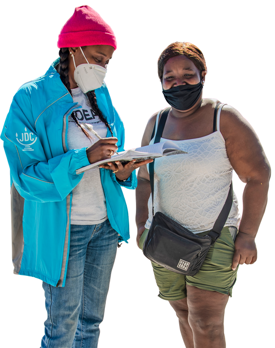 A JDC humanitarian aid worker in the Bahamas writing in a notepad next to an aid recipient.