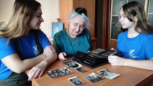 Two JDC volunteers keep an elderly client company.