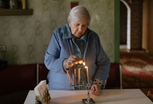 An elderly JDC client lights her chanukiah at her home in Chișinău, Moldova. 
